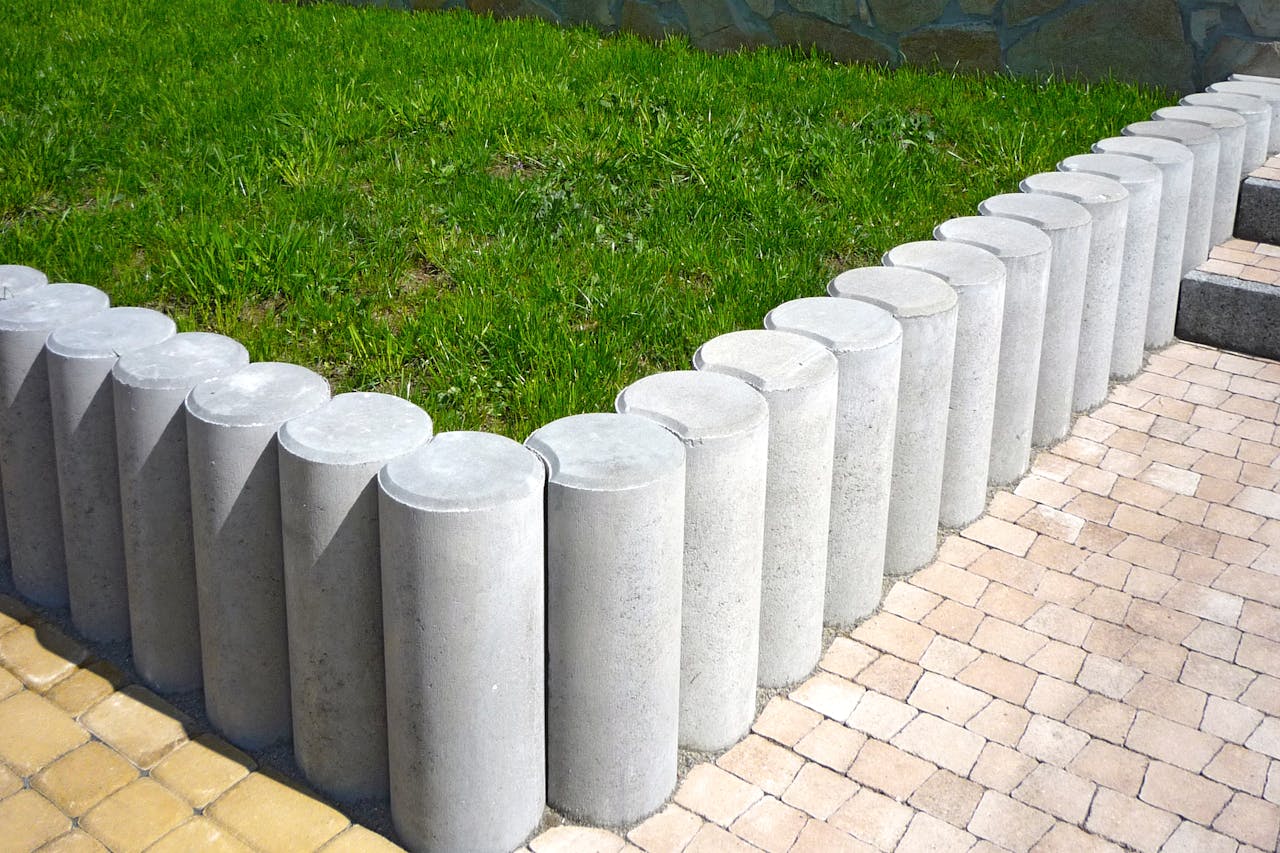Cylindrical concrete blocks form a stylish lawn boundary, enhancing garden aesthetics.